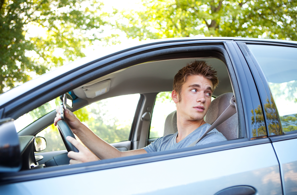 Young male driving a car.