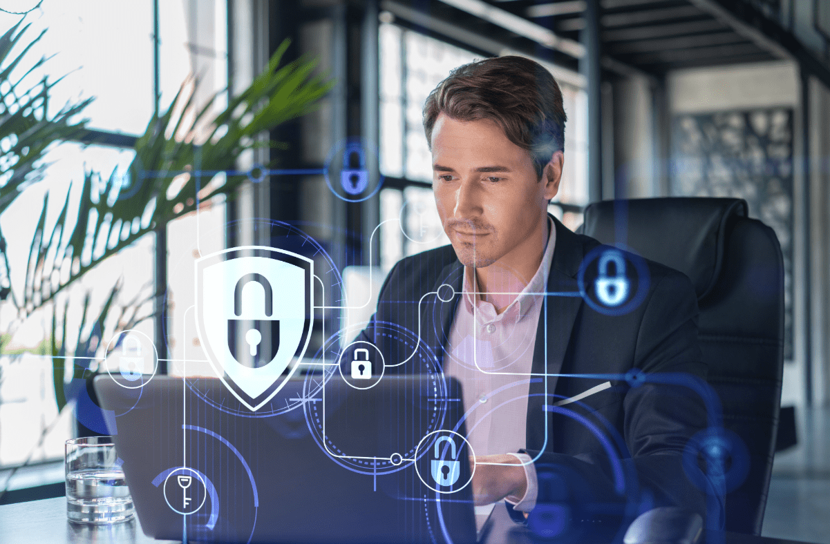 Man in an office sitting at a computer reviewing his business cyber liability insurance.