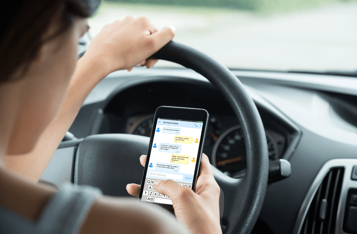 Distracted driver. Woman behind the wheel of the car using her cell phone.