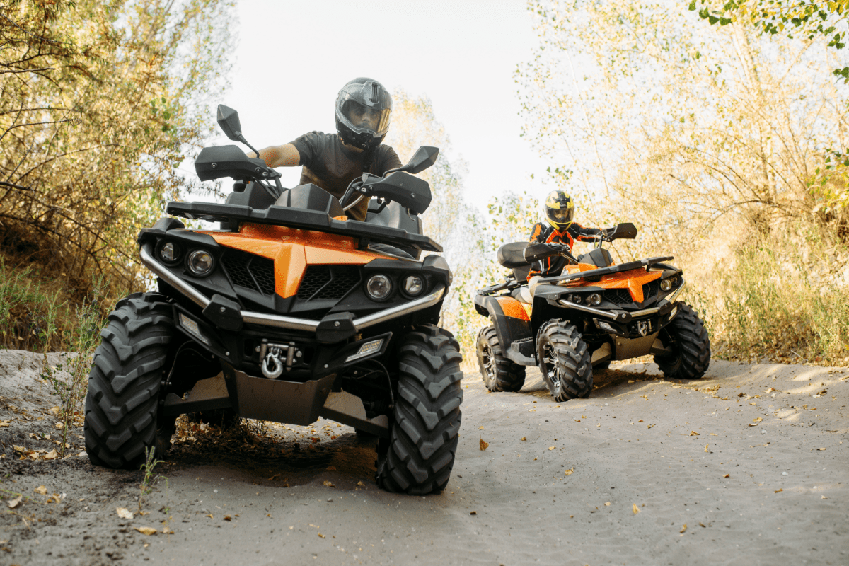 Two adults on ATVs on a off road trail.