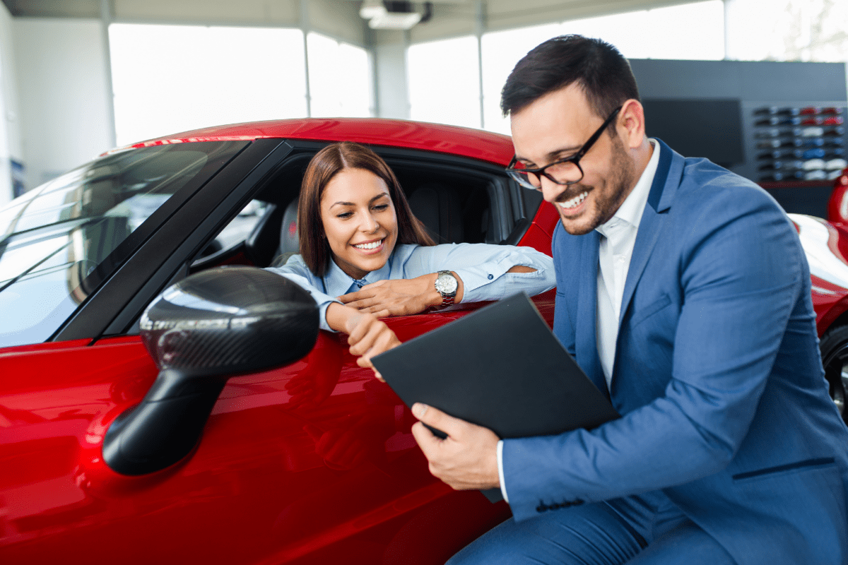 Woman sitting in drivers seat discussing car insurance with insurance agent