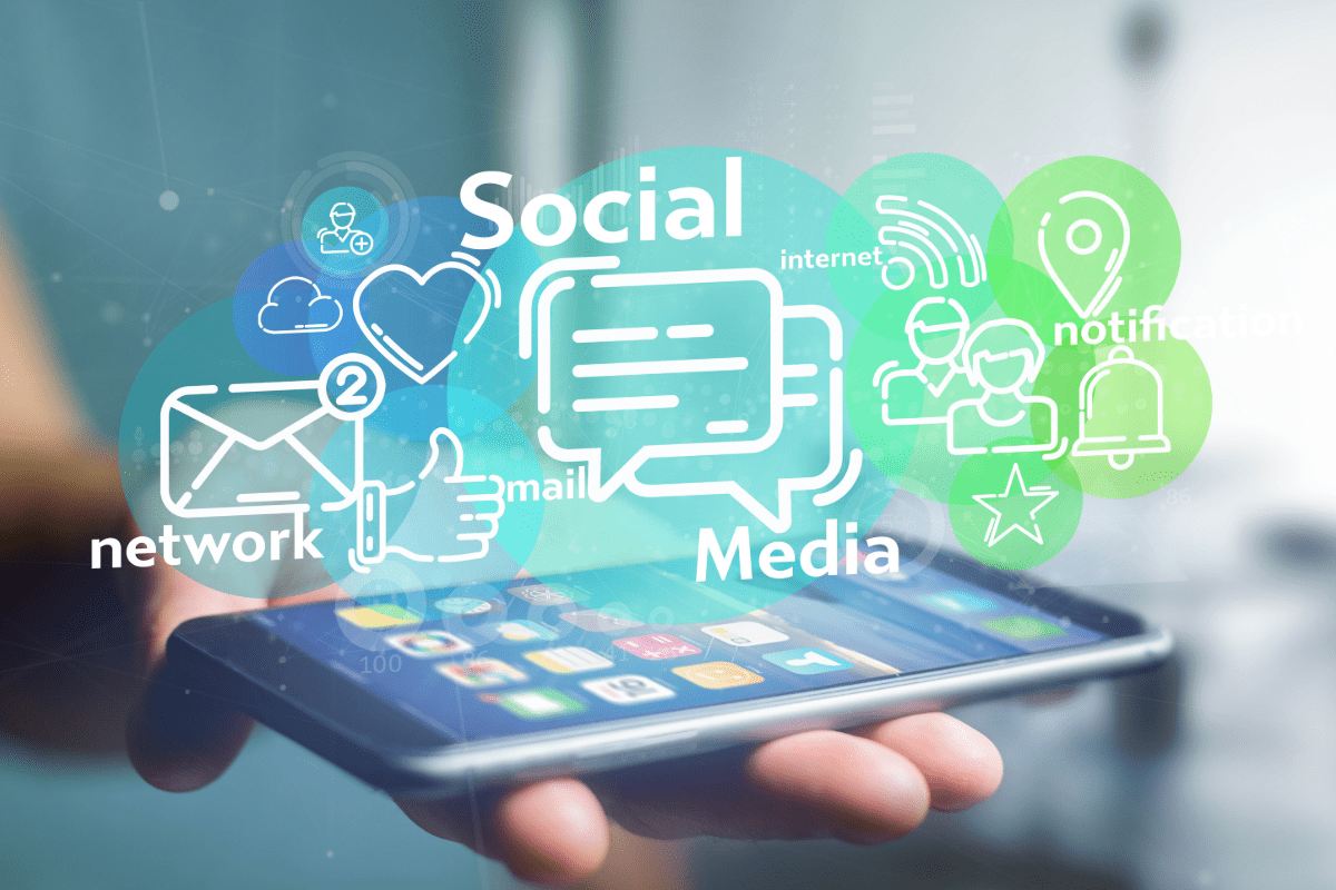 Smart phone in a person's palm with social media graphics hovering above the screen.