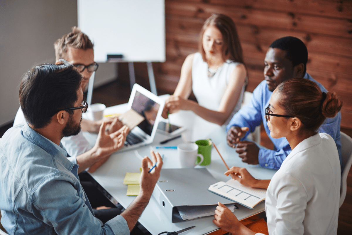 Business professionals sitting around meeting table discussing insurance needs.