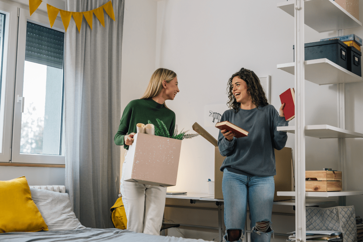 Two young college student moving into their dorm and discussing renters insurance.