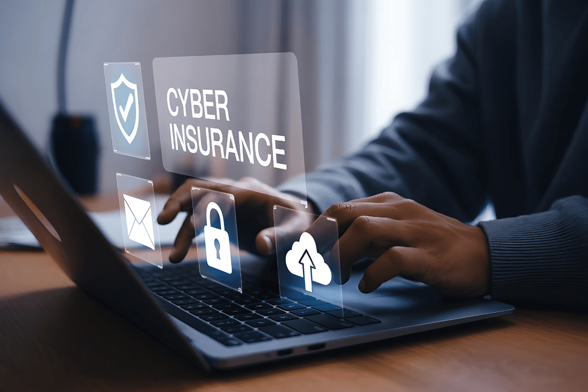 Man typing on laptop with cyber insurance graphic in foreground
