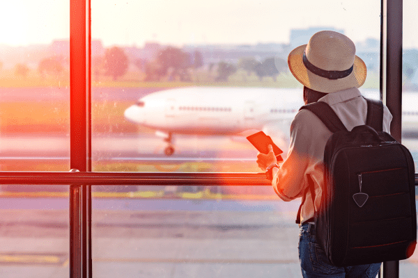 Traveler looksing out the window at an airport at a airplane taxiing