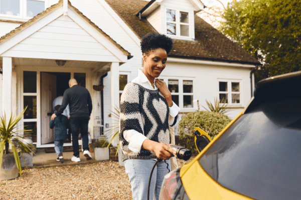 Mom plugging in EV in from of home while dad and son head inside
