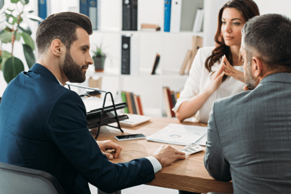 Business meeting three individual sitting around a table discussing business insurance