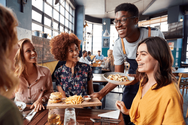 Waiter serving food to a table of hungry restaurant customers